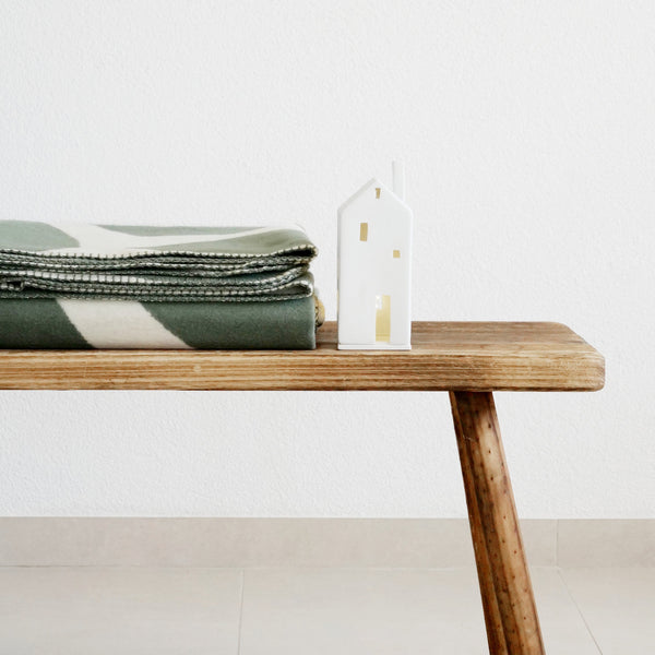 XL Kuscheldecke BJÖRK mit grünem, floralem Motiv gefaltet auf Holzbank