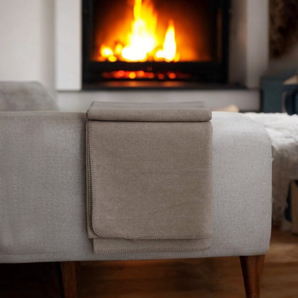 extra große Kuscheldecke THO in braun aus recycelter Baumwolle in Deutschland hergestellt vor einem Kamin im WInter
