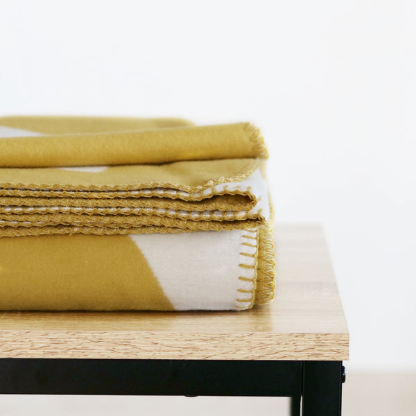 RIEMA Kuscheldecke AURORA aus 100% Bio-Baumwolle in gelb und einem Blattmotiv gefaltet