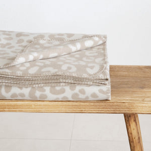 RIEMA XL Baumwolldecke aus recycelter Baumwolle mit Leopardenmuster auf Holzbank