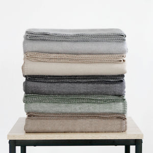 RIEMA XL Kuscheldecke BJÖRK recycelte Baumwolle, 150x230 cm in braun, grau, dunkelgrau, grün, beige, gefaltet und gestapelt